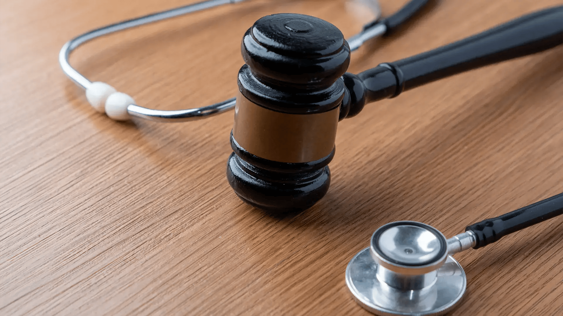 Mazo judicial y estetoscopio sobre una mesa de madera, simbolizando una demanda por negligencia médica.