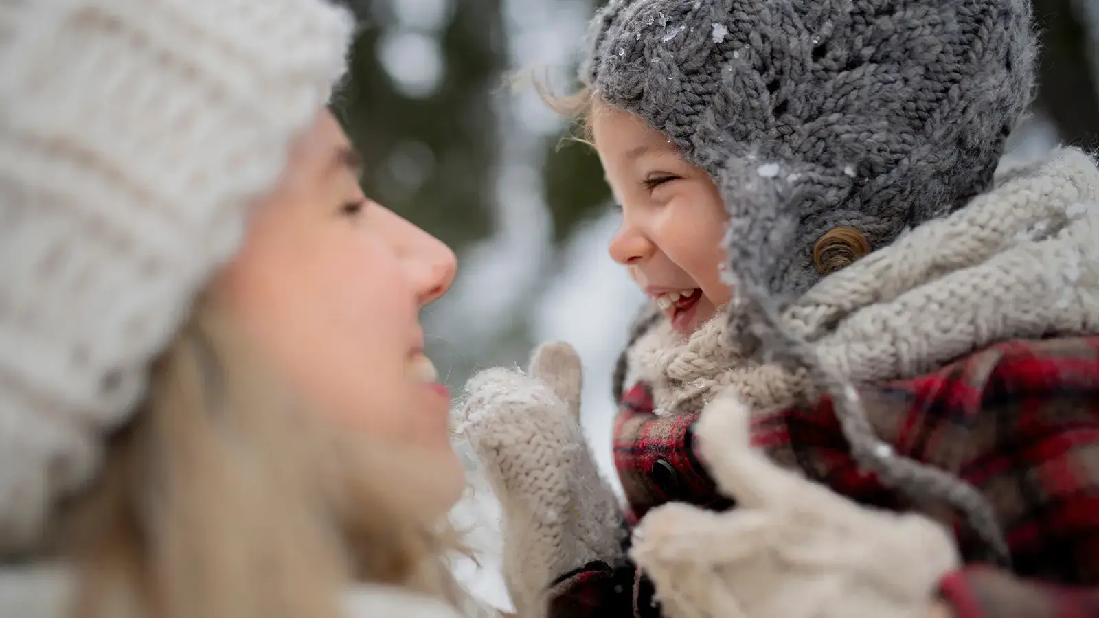Relación directa y regular. Madre levantando a su hija pequeña en la nieve