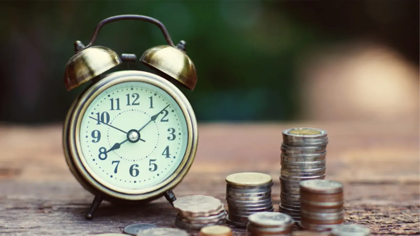 Tranquilidad financiera. Reloj despertador junto a torres de monedas.